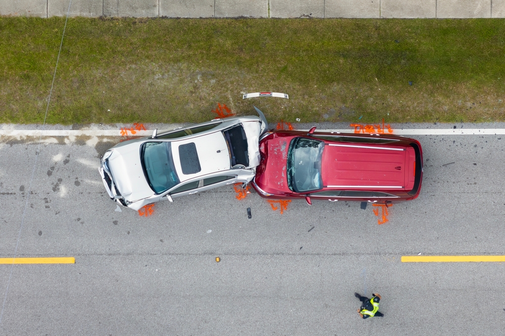 Overhead view of a damaged car after a collision, showing significant impact on the driver's side.