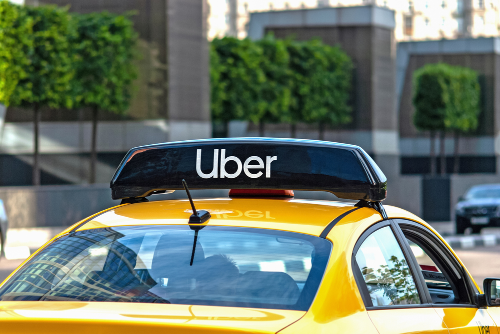 Yellow car with an Uber sign on the roof driving in a city