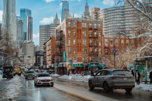 Snowy New York City street with traffic near brick apartment buildings